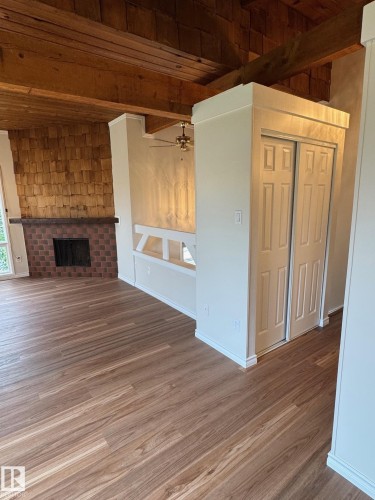 Open-concept living area featuring wood-finish flooring, exposed beam ceiling, a brick-surround fireplace with a wood mantel, and an integrated built-in bench seating area - 482 Lee Ridge Road Nw, Edmonton, AB 