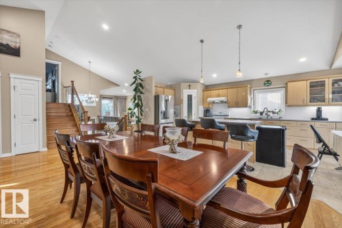 Open-concept dining area featuring wood-finish flooring, a vaulted ceiling, and a visible kitchen with light wood cabinetry - 6050 164A Avenue, Edmonton, AB - Indoor Photo Showing Dining Room