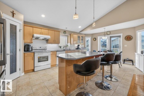 Kitchen featuring light wood cabinetry, white appliances, tile flooring, and a central island with a countertop - 6050 164A Avenue, Edmonton, AB - Indoor Photo Showing Kitchen