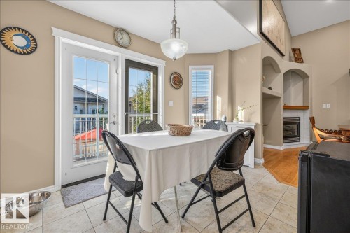 Dining area with tile flooring and a white glass-paneled door opening to an exterior balcony - 6050 164A Avenue, Edmonton, AB - Indoor Photo Showing Dining Room