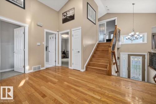 Entryway featuring wood-finish flooring, a grand staircase with wood railing and wrought iron spindles, high vaulted ceilings, and multiple doorways - 6050 164A Avenue, Edmonton, AB - Indoor Photo Showing Other Room