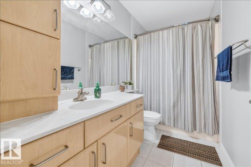 Bathroom featuring a light wood-finish vanity with a single basin sink, light-toned countertop, and ample storage cabinetry - 6050 164A Avenue, Edmonton, AB - Indoor Photo Showing Bathroom