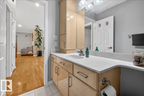 Bathroom vanity featuring wood-finish cabinetry, a solid surface countertop with an integrated sink, and an expansive wall mirror - 6050 164A Avenue, Edmonton, AB - Indoor Photo Showing Bathroom