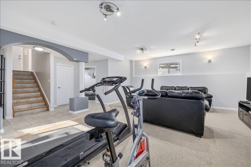 Versatile lower level featuring a tiled entry, carpeted recreation area, painted accent archway, recessed lighting, and wall sconces - 6050 164A Avenue, Edmonton, AB - Indoor