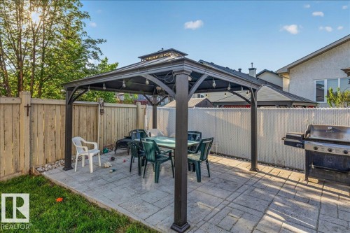Stamped concrete patio featuring a gazebo with integrated lighting, surrounded by wood fencing and a patch of green lawn - 6050 164A Avenue, Edmonton, AB - Outdoor With Deck Patio Veranda