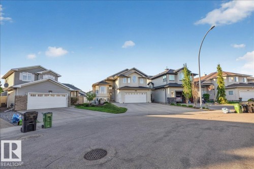 Suburban streetscape featuring a gray-sided residence with white trim, an attached two-car garage, and a bay window - 6050 164A Avenue, Edmonton, AB - Outdoor With Facade