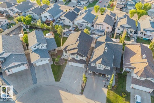 Residential street with multiple properties featuring asphalt shingle roofs, attached garages, and paved driveways - 6050 164A Avenue, Edmonton, AB - Outdoor With View