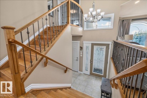 Grand foyer featuring a wood-finish staircase with wrought iron balusters, a decorative glass entry door with sidelights, and tiled flooring - 6050 164A Avenue, Edmonton, AB - Indoor Photo Showing Other Room