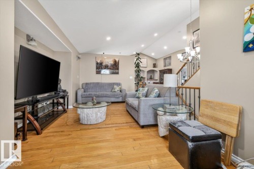 Open-concept living area featuring hardwood flooring, recessed ceiling lighting, a vaulted ceiling, and a staircase with wrought iron balusters - 6050 164A Avenue, Edmonton, AB - Indoor Photo Showing Living Room