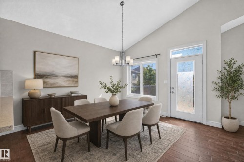 Dining space with vaulted ceilings, wood-finish flooring, a contemporary chandelier, large window, and a door with decorative glass - 1346 Cunningham Drive, Edmonton, AB 