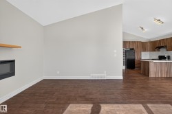 Open-concept living area featuring a built-in fireplace with a wood-finish mantel, wood-finish flooring, and vaulted ceilings - 