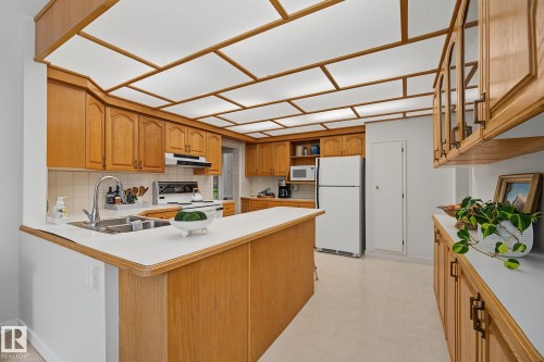 Kitchen featuring wood-finish cabinetry, white countertops, and a full light panel ceiling - 9516 146 Street, Edmonton, AB 