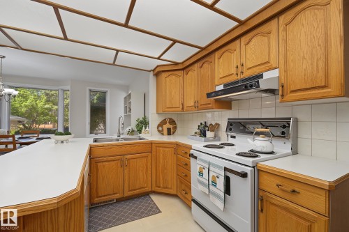 Kitchen featuring wood cabinetry, white countertops, a white electric range, and a tile backsplash - 9516 146 Street, Edmonton, AB 