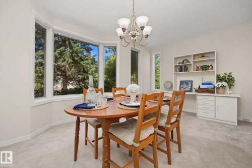 Bay window with multiple panels, a built-in hutch with shelving and cabinetry, recessed ceiling, and an overhead chandelier light fixture - 9516 146 Street, Edmonton, AB 