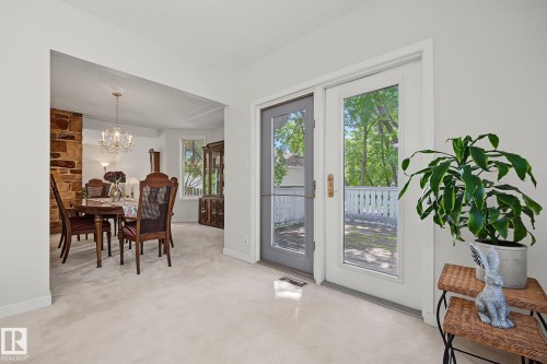 Dining area featuring a stone accent wall, chandelier lighting, and a bay window - 9516 146 Street, Edmonton, AB 