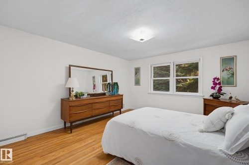 Room featuring wood-finish flooring, white walls, and a window providing natural illumination - 9516 146 Street, Edmonton, AB 