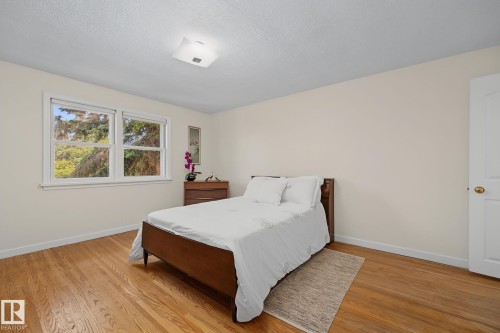 Bedroom featuring hardwood flooring, white baseboards, and two windows providing natural light - 9516 146 Street, Edmonton, AB 