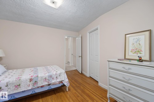 Hardwood-finish flooring throughout, smooth neutral walls, and a textured ceiling with a flush-mount light fixture - 9516 146 Street, Edmonton, AB 