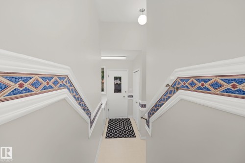 Staircase featuring decorative tile inlay and white trim - 9516 146 Street, Edmonton, AB 