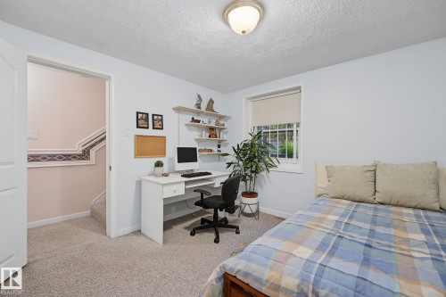Carpeted room with light blue walls and a built-in white desk featuring shelving - 9516 146 Street, Edmonton, AB 