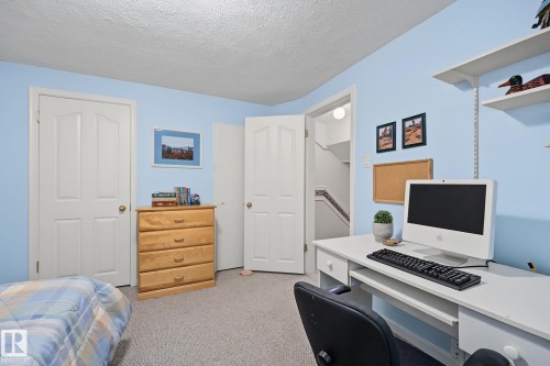 Carpeted room featuring light blue painted walls, white trim, and a white paneled door - 9516 146 Street, Edmonton, AB 