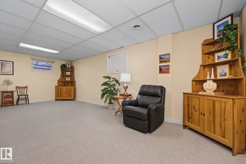 Expansive carpeted room featuring a drop ceiling with recessed lighting, cream-colored walls, and white trim - 9516 146 Street, Edmonton, AB 