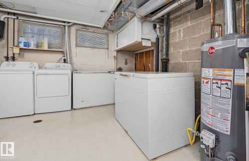 Utility room featuring a water heater, exposed ductwork, and block wall construction - 9516 146 Street, Edmonton, AB 