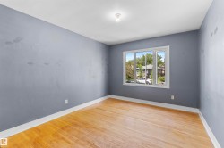 Room featuring wood-finish flooring, a multi-pane window, white trim, and a ceiling-mounted light fixture - 