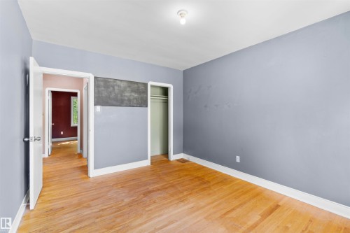 Hardwood flooring extends throughout this room, featuring light gray walls, white trim, and a recessed clothing rod - 10607 73 Ave, Edmonton, AB 
