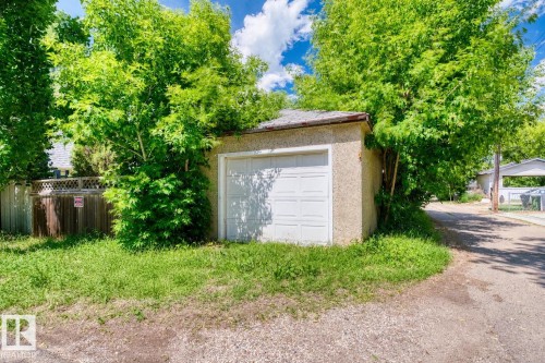 Detached single-car garage featuring a white panel door and stucco exterior - 10607 73 Ave, Edmonton, AB 