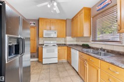 Kitchen featuring light wood cabinetry, a dual basin stainless steel sink, tiled backsplash, and light-toned tile flooring - 