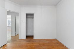 Room featuring wood-finish flooring, white walls, and a recessed closet with shelving and a hanging rod - 
