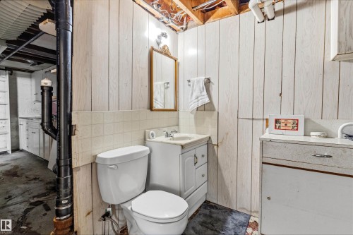 Bathroom featuring a white toilet, white vanity with integrated sink, and a framed mirror - 11619 123 Street, Edmonton, AB 