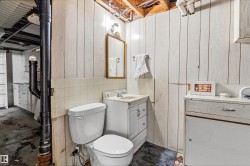 Bathroom featuring a white toilet, white vanity with integrated sink, and a framed mirror - 