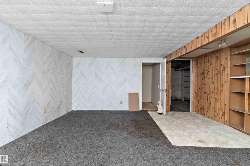 Interior space featuring a patterned wall finish, a textured drop ceiling, and mixed flooring - 11619 123 Street, Edmonton, AB 
