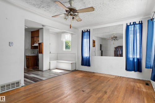 Expansive living area featuring hardwood flooring, a ceiling fan with light fixture, and a built-in bench seating area - 11619 123 Street, Edmonton, AB 