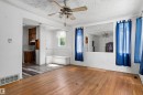 Expansive living area featuring hardwood flooring, a ceiling fan with light fixture, and a built-in bench seating area - 11619 123 Street, Edmonton, AB 