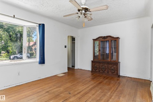 Hardwood flooring featuring an overhead ceiling fan, white walls, and a large window - 11619 123 Street, Edmonton, AB 