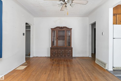 Room featuring wood-finish flooring, white painted walls, and an arched doorway - 11619 123 Street, Edmonton, AB 