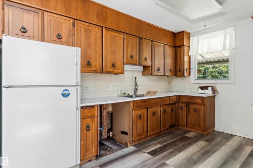 Kitchen featuring wood cabinetry, light countertops, and a tile backsplash - 11619 123 Street, Edmonton, AB 