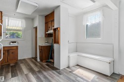 Kitchen area featuring wood-finish flooring, two windows, and built-in white banquette seating - 