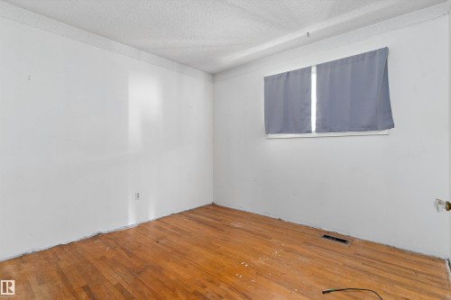 Hardwood flooring with a natural finish, white painted walls, and a textured ceiling - 11619 123 Street, Edmonton, AB 