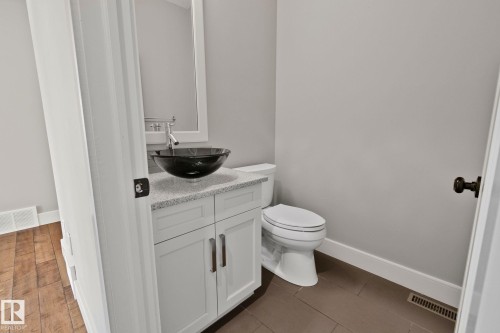 Modern bathroom vanity featuring white cabinetry, a light speckled countertop, and a contemporary vessel sink with a wall-mounted faucet - 9 Greenfield Wynd, Fort Saskatchewan, AB - Indoor Photo Showing Bathroom