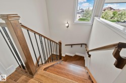 Hardwood staircase featuring dark wood newel posts, handrails, and black metal balusters - 
