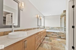 Bathroom featuring natural stone tile flooring, a dual vanity with vessel sinks, light wood-finish cabinetry, and a walk-in shower with a built-in tub - 