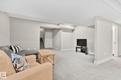 Spacious interior room featuring light gray walls, plush gray carpeting, white trim, and a white ceiling - 9 Greenfield Wynd, Fort Saskatchewan, AB - Indoor