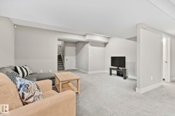 Spacious interior room featuring light gray walls, plush gray carpeting, white trim, and a white ceiling - 