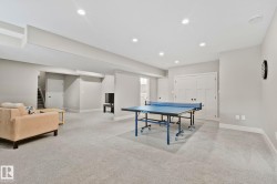 Spacious finished lower level featuring recessed lighting, light-toned carpeting, neutral wall color, and double panel doors - 