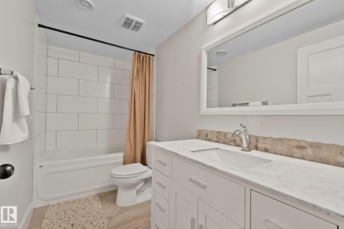 Bathroom featuring a white vanity with a marble-look countertop, an undermount sink, and a chrome faucet - 9 Greenfield Wynd, Fort Saskatchewan, AB - Indoor Photo Showing Bathroom