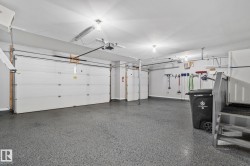 Spacious garage featuring two sectional doors, a durable epoxy-coated floor, overhead lighting, and built-in wall storage solutions - 